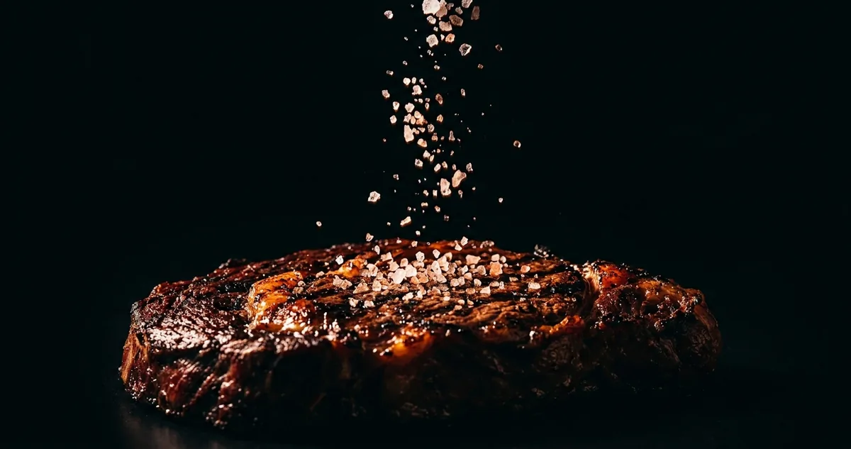 Pe&ccedil;a de picanha crua vista de lado numa t&aacute;bua, com a capa de gordura raspada fina e uma faca de a&ccedil;ougue ao lado