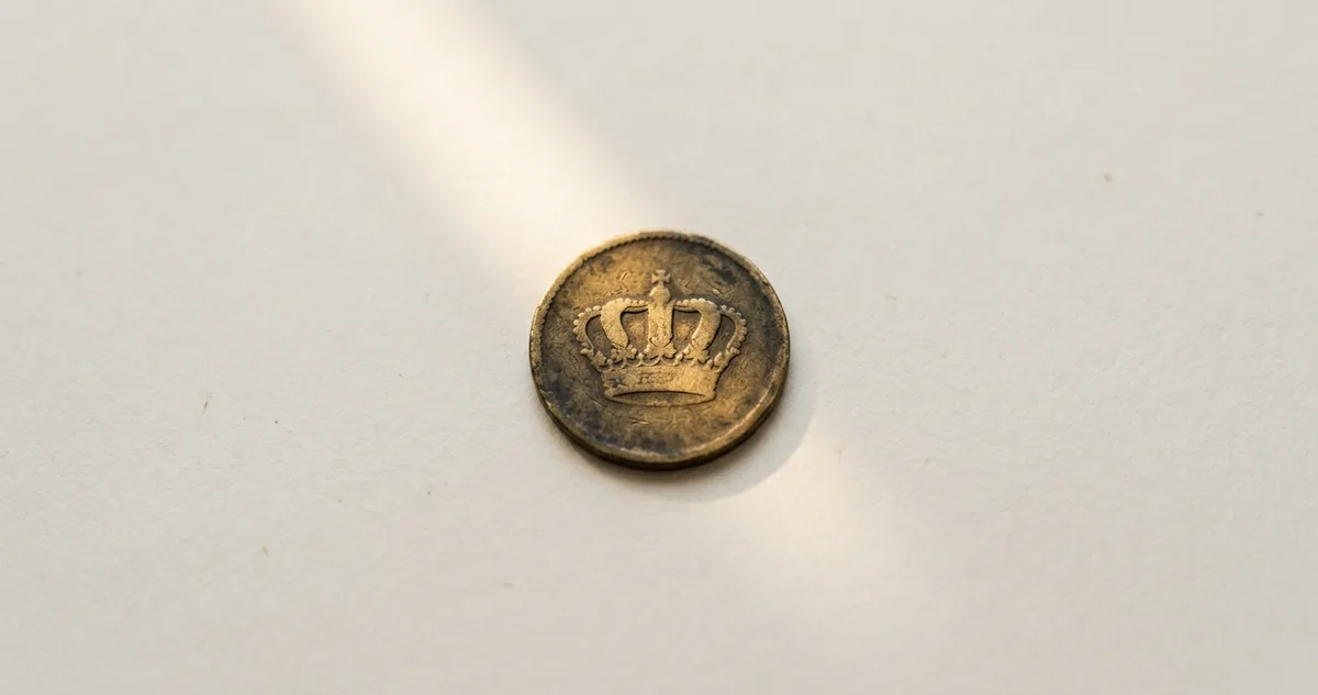 Moeda de ouro do Império com o brasão coroado ao lado de uma moeda de real com a efígie da República.