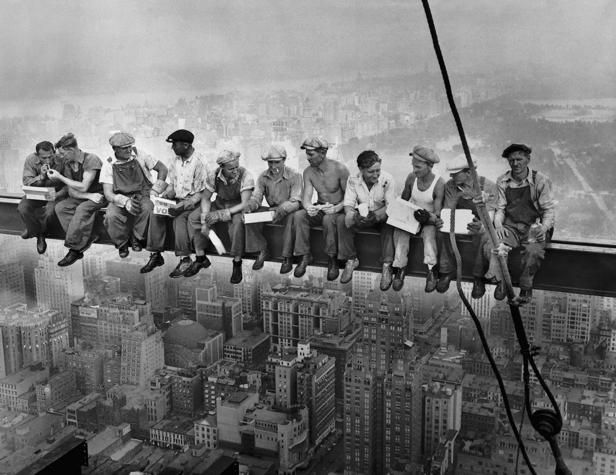 Onze operários sentados lado a lado numa viga de aço suspensa sobre Manhattan, almoçando e fumando, no 69º andar do RCA Building em 1932.