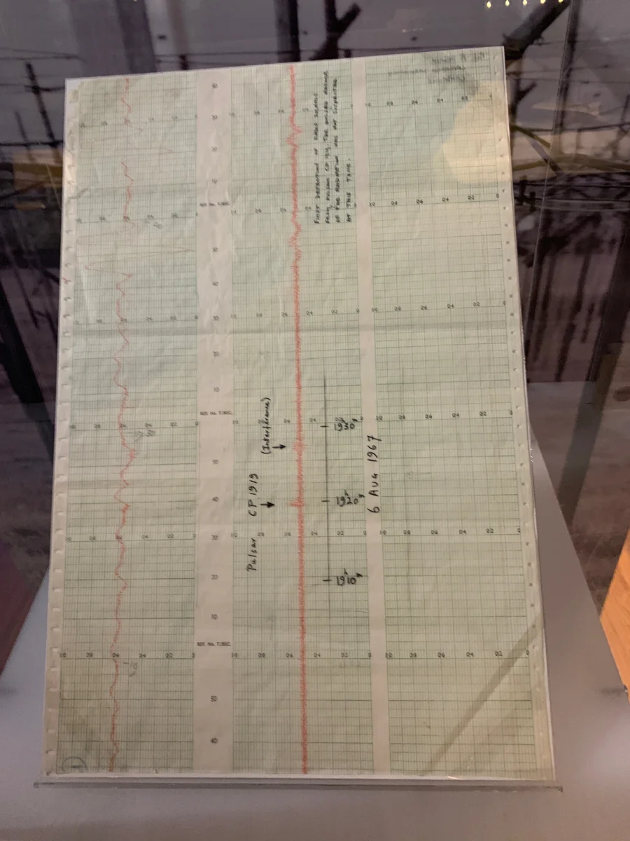 Tira de papel milimetrado do radiotelescópio do Mullard Radio Astronomy Observatory, em Cambridge, com o traço de rádio do primeiro pulsar identificado, o LGM-1, examinado por Jocelyn Bell em agosto de 1967.