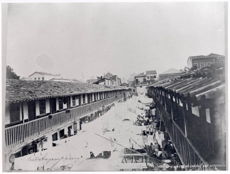 Rua do Hospício, no centro do Rio de Janeiro, fotografada em 1905 por Augusto Malta, com sobrados de dois andares dos dois lados de uma via de sete metros de largura.