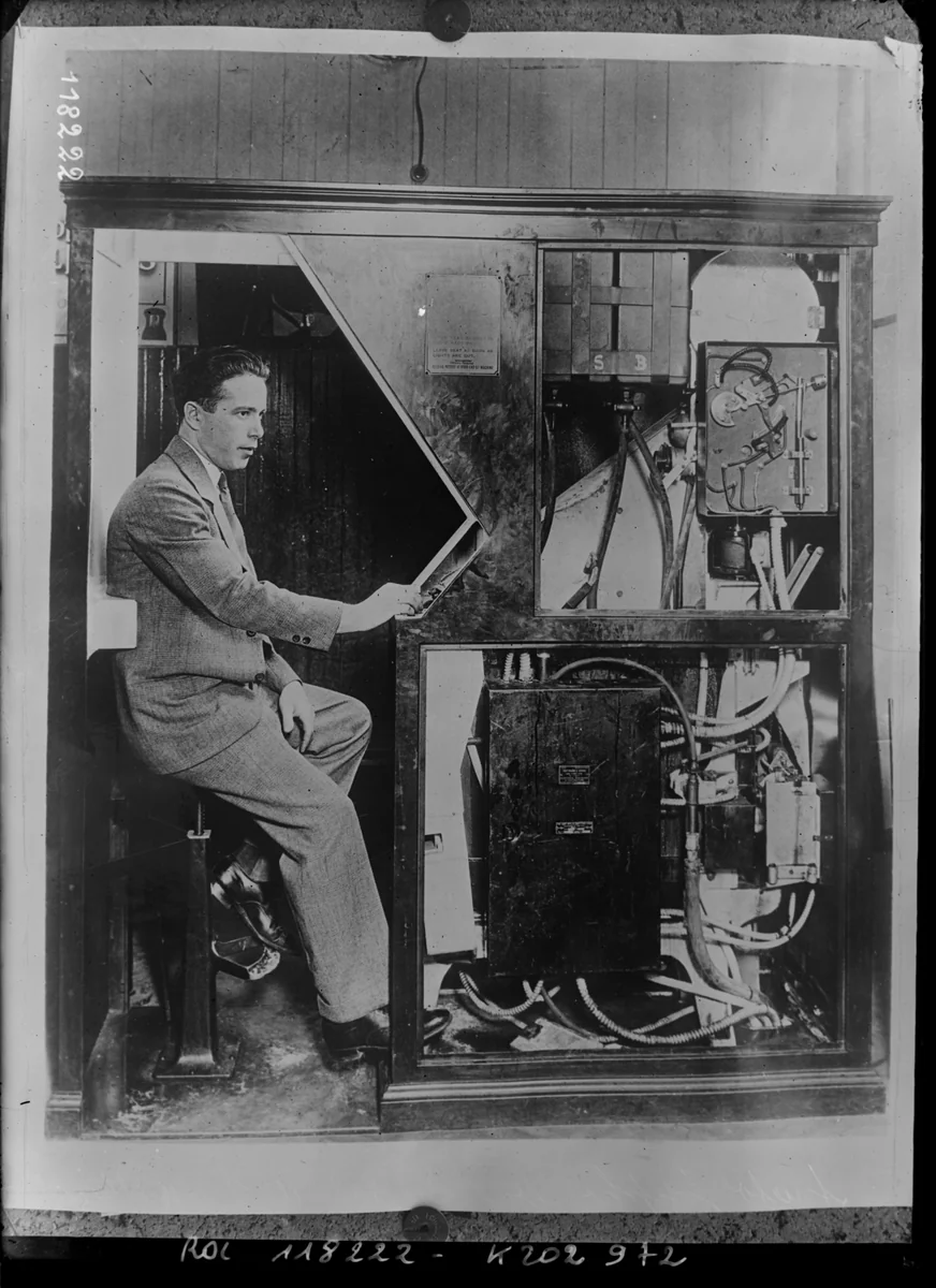 Fotografia da Agence Rol, 1927: Anatol Josepho sentado dentro da cabine do Photomaton, com a máquina aberta