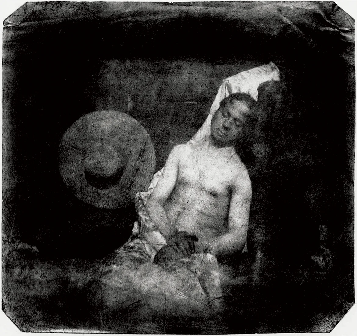 Hippolyte Bayard, de tronco nu e olhos fechados, sentado e tombado contra uma parede, posando como um afogado no necrotério