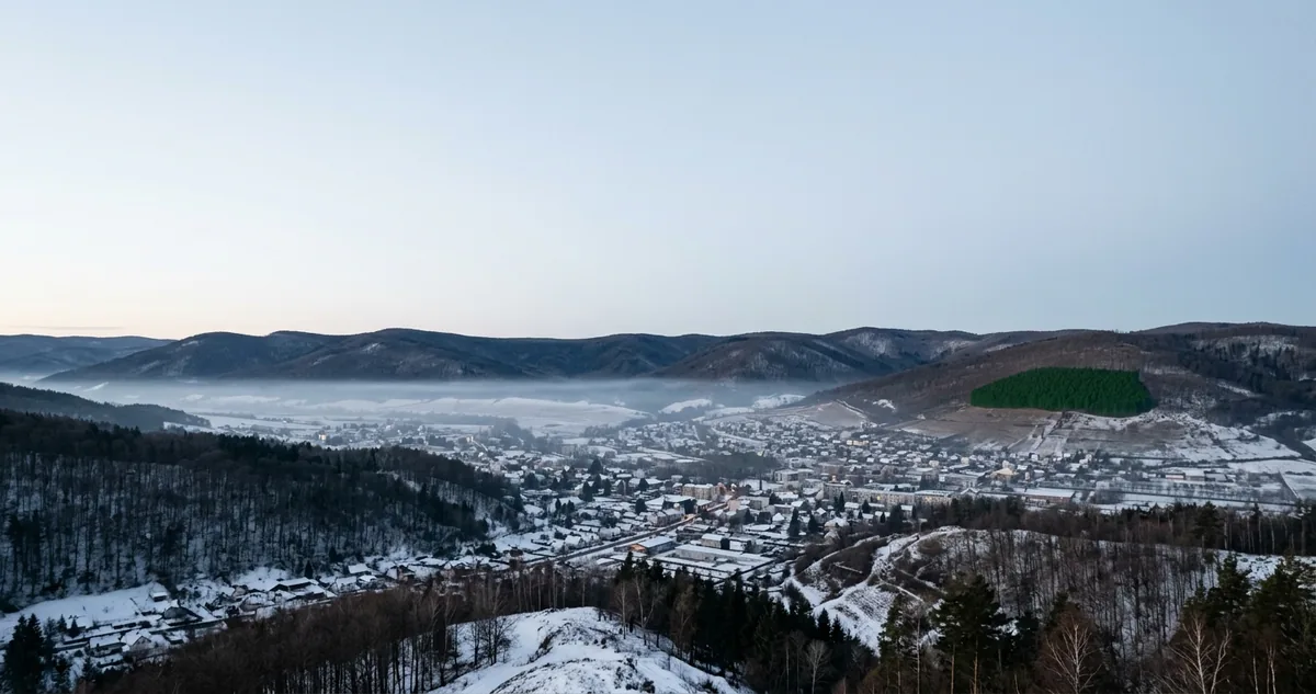 Ulan Bator coberta de névoa e fumaça numa manhã de inverno, com os prédios do centro e as montanhas ao fundo.