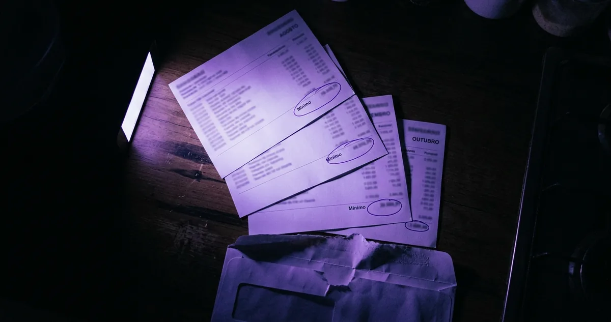 Envelope bancário entreaberto com uma nota dobrada sobre um cartão de crédito.