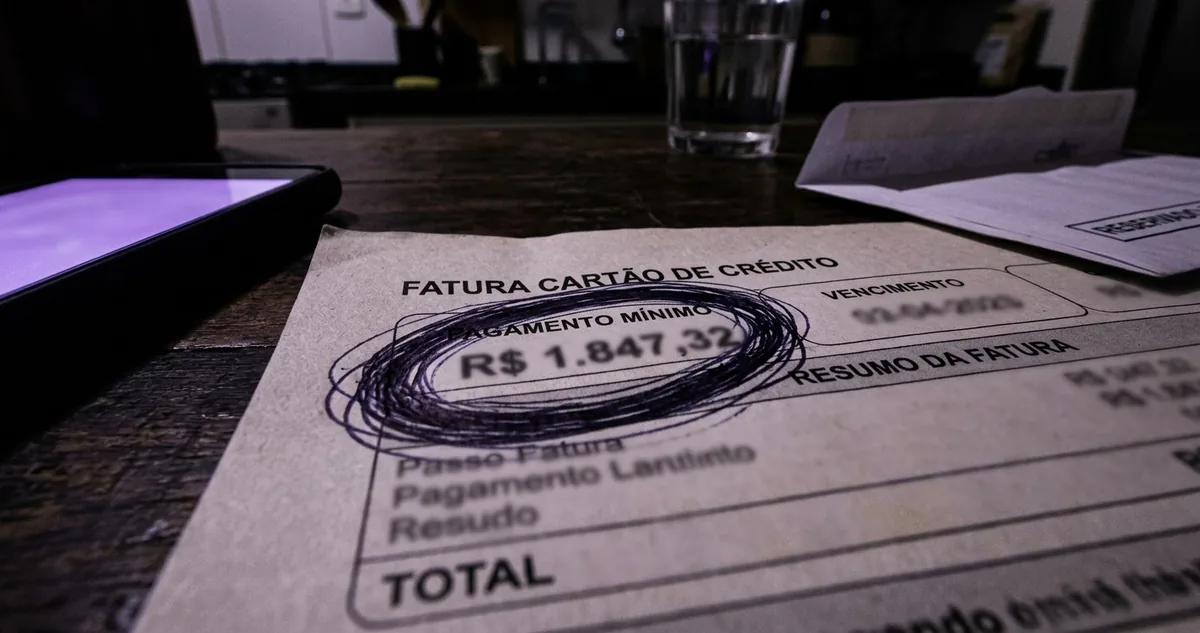 Cartão de benefício sobre um envelope, ao lado de um carnê de parcelas.