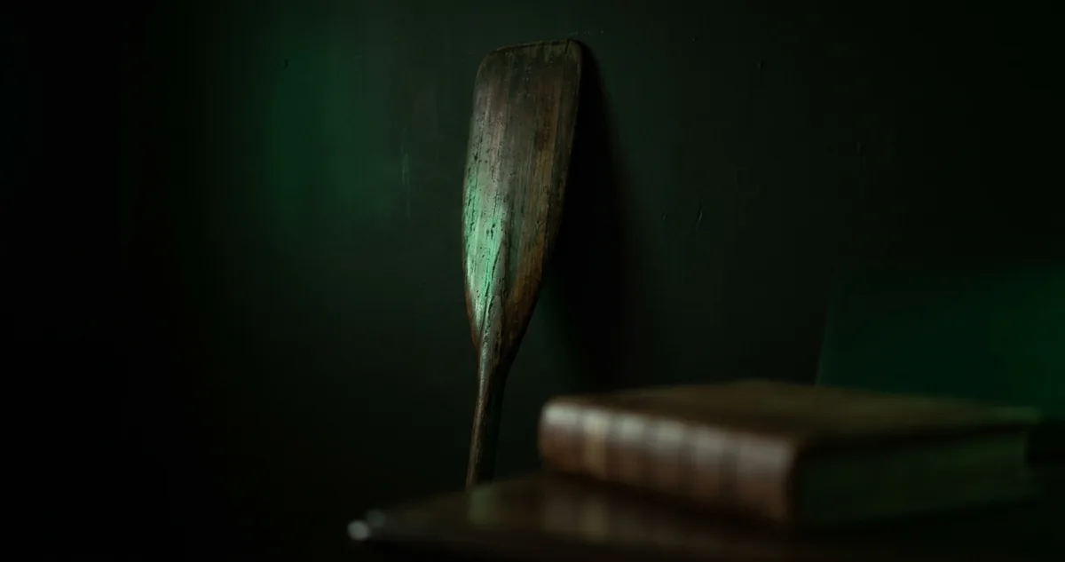 Livro de assentos aberto sobre mesa escura, com tinteiro de vidro e pena gasta ao lado.